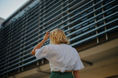 Rear view of woman standing against railing against building