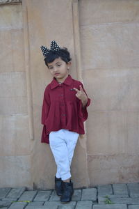 Portrait of girl standing against wall