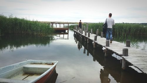 Rear view of people walking on pier over lake