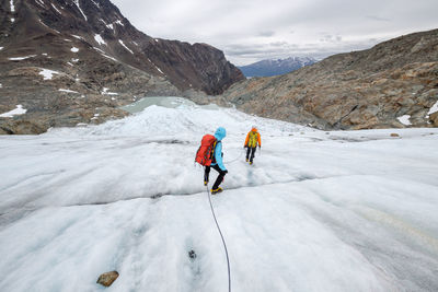 Rear view of people hiking on snow covered mountain