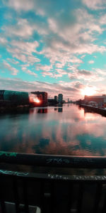 Illuminated city by sea against sky during sunset