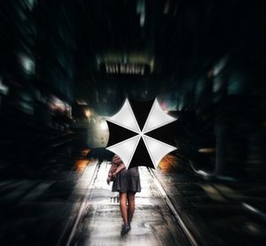 Rear view of woman standing on wet umbrella