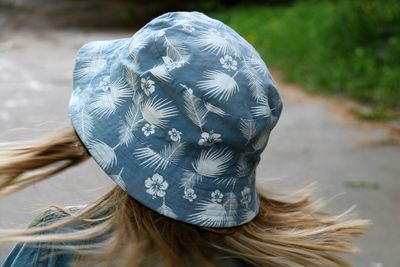 Close-up of woman wearing bucket hat while standing on footpath