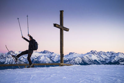 Man snowboarding by snowcapped mountain against sky