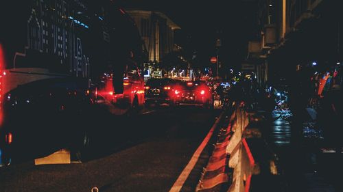 Illuminated city street by buildings at night