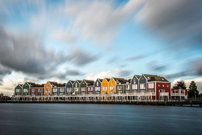 Buildings by river against sky in city