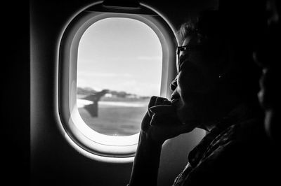Portrait of man looking through airplane window
