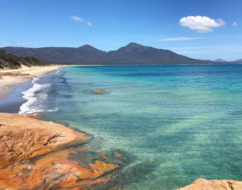 Scenic view of sea and mountains against blue sky