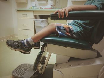 Low section of boy sitting on dentist chair