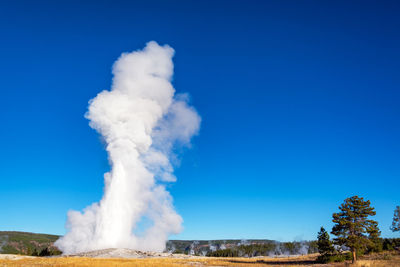 Steam emitting from landscape against sky