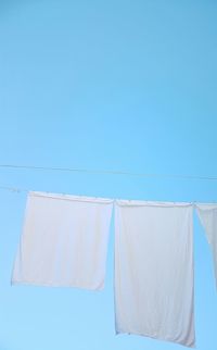 Close-up of clothes drying on clothesline against clear blue sky