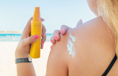 Midsection of woman holding umbrella on beach