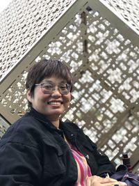 Portrait of young woman standing against building