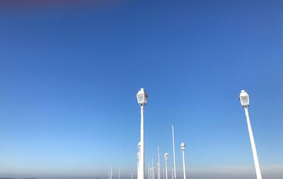 Low angle view of street lights against clear blue sky