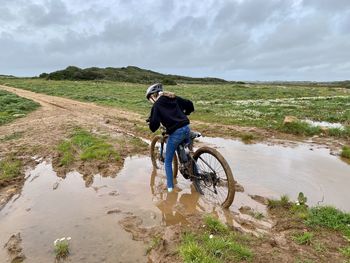 Teenage girl riding a mountain bike on a dirt trail and getting stuck in the mud