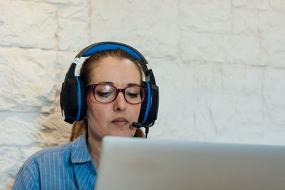 Woman working with her laptop and is focused on listening with her headphones