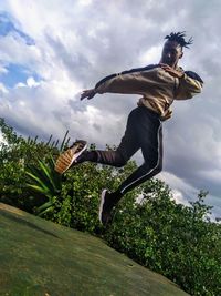 Low angle view of man jumping against sky