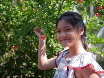 Portrait of young woman standing against trees