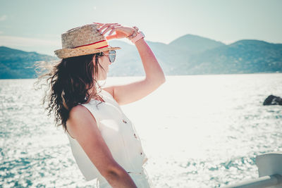 Rear view of woman drinking water while standing at beach