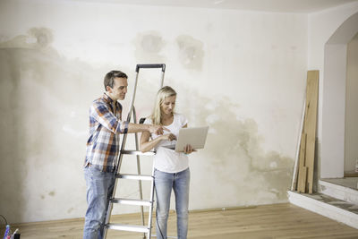 Couple using laptop while standing at home