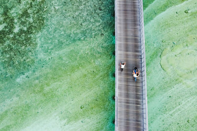 Woman and kid riging their bikes over the ocean. aerial view