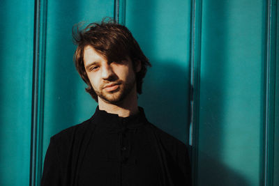 Portrait of young man standing against blue wall