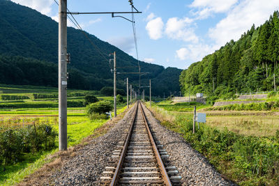 Railroad tracks by trees against sky