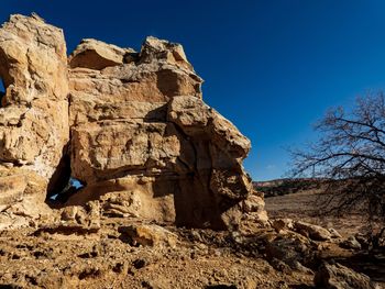 Low angle view of rock formation suggesting human characteristics against clear blue sky