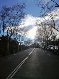 Road amidst bare trees against sky