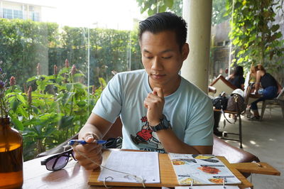 Handsome man sitting reading paper while sitting at restaurant table 