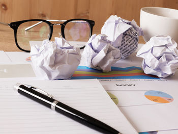 High angle view of pen with crumpled papers and financial reports on desk in office