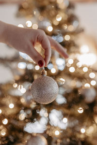 Cropped hand of woman holding illuminated christmas tree