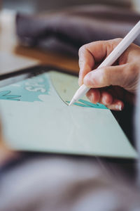 Cropped hand of woman writing in ipad