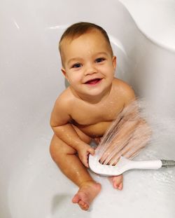 Portrait of cute baby boy sitting in bathtub