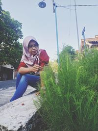 Portrait of young woman sitting on mobile phone