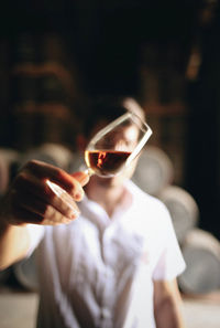 Close-up of man holding drink in glass over face