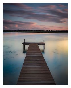 Pier over lake against sky during sunset