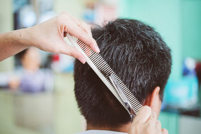 Cropped hands of woman cutting man hair