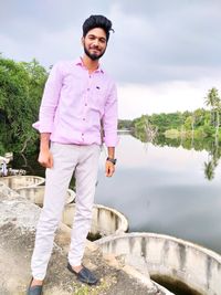 Portrait of young man standing by lake