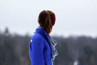 Side view of woman standing against sky during winter