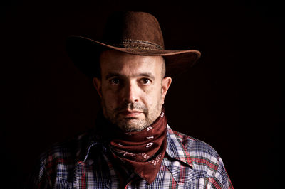 Portrait of man wearing hat against black background