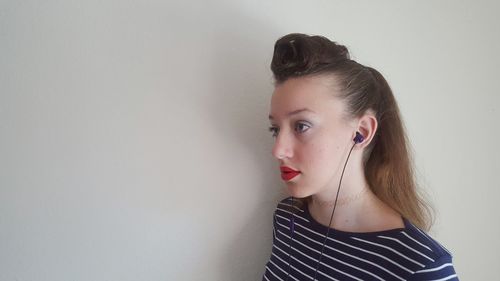 Portrait of beautiful young woman standing against wall