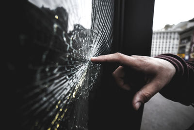 Close-up of hand on broken window