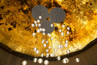 Low angle view of illuminated chandelier hanging on ceiling