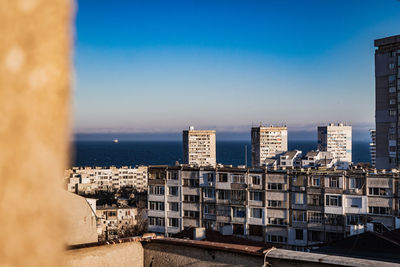 Sea by buildings against clear blue sky