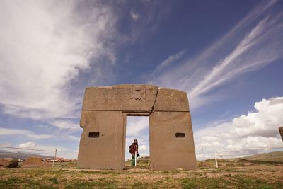 Woman standing by old ruin against sky