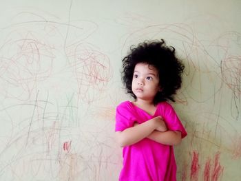 Portrait of girl standing against wall