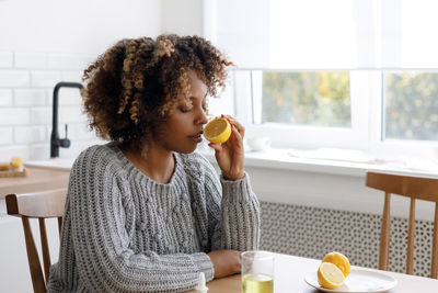 Young woman using mobile phone while sitting at home