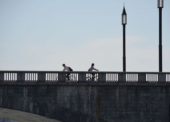 People on footbridge against sky
