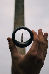 Close-up of man holding hand against the sky